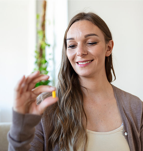 Smiling woman holding compounded medication taken out of blister packaging to help her stay organized.